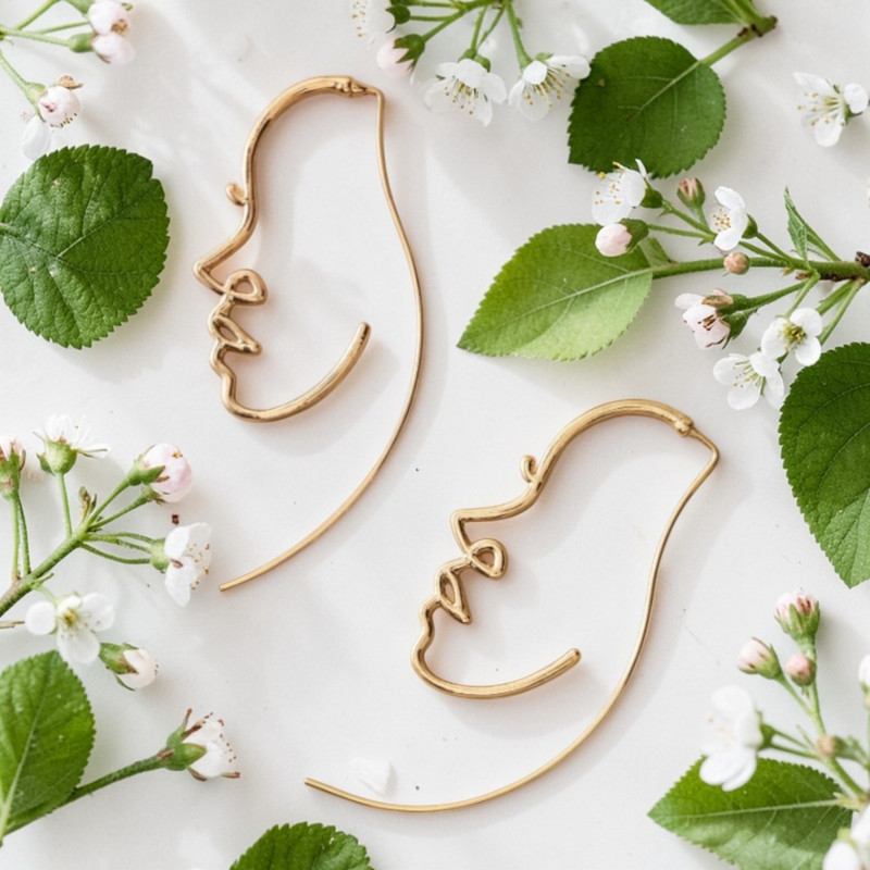 Boucles d'oreilles dorées profil visage abstrait